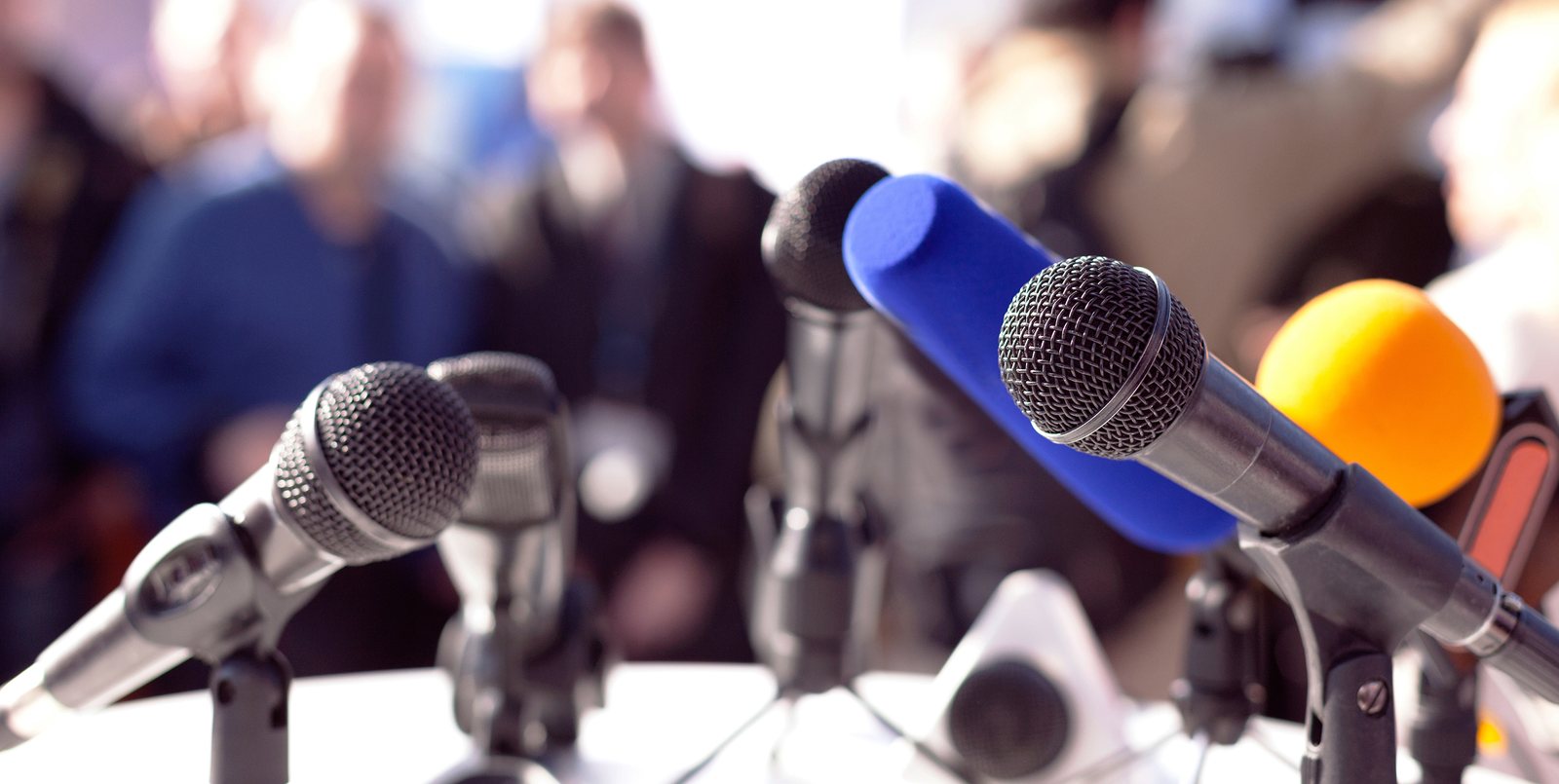 Mikrofone mehrerer Sender auf einem Pult bei einer Pressekonferenz