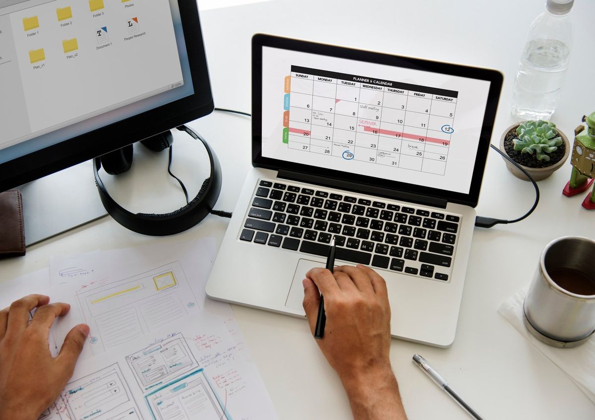 Terminplanung am Schreibtisch mit Laptop und Kalender